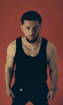 Foto von BAUSA in einem schwarzen Tanktop, wie er in die Kamera schaut